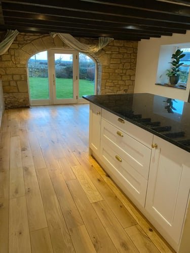 Restored oak floor in a farmhouse kitchen with a stone arch